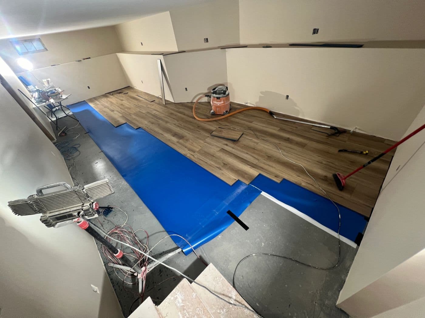 Luxury vinyl plank flooring being installed over underlayment during a renovation