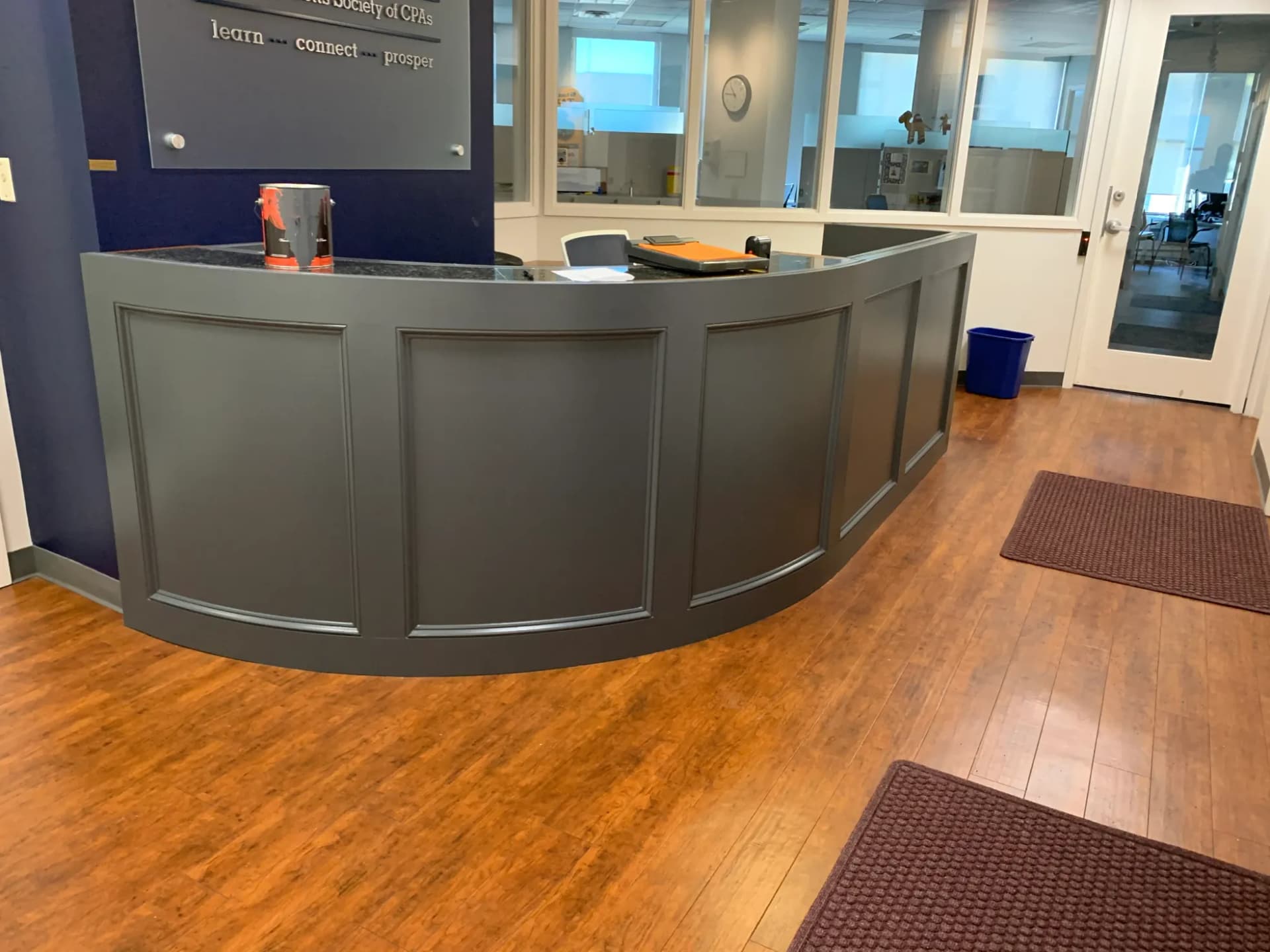 A completed curved commercial reception desk with painted panel millwork and a stone countertop