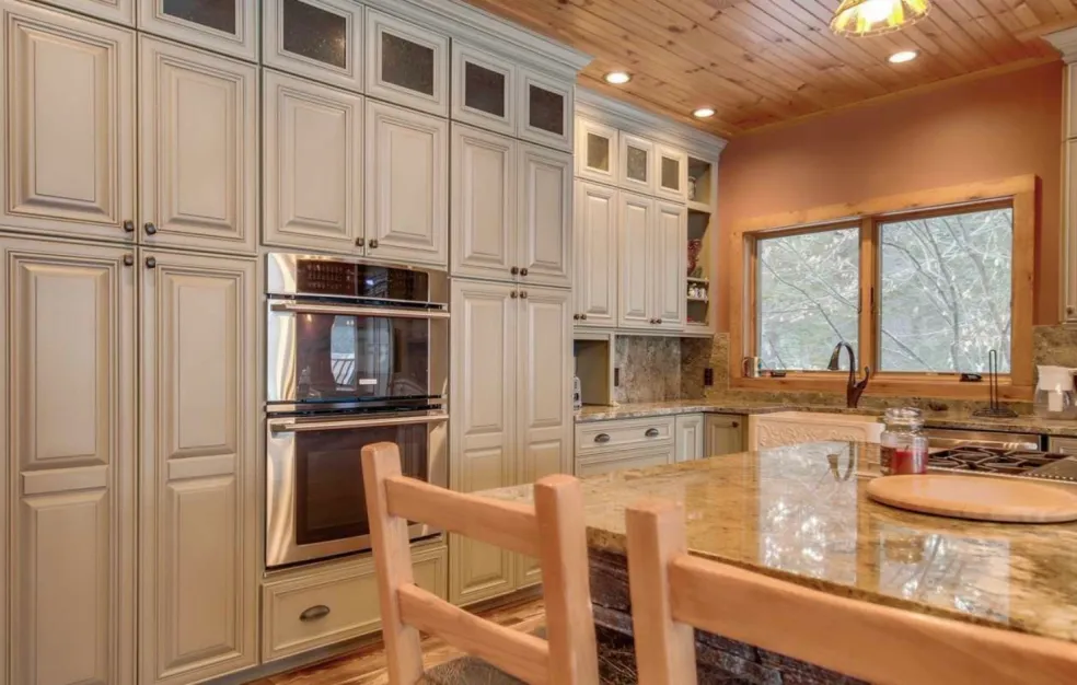 A finished custom kitchen with raised-panel cabinetry, granite countertops, and stainless appliances